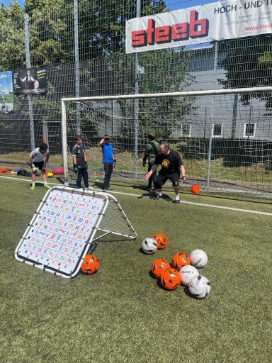 Kinder trainieren auf einem Fußballplatz mit Toren und Bällen.