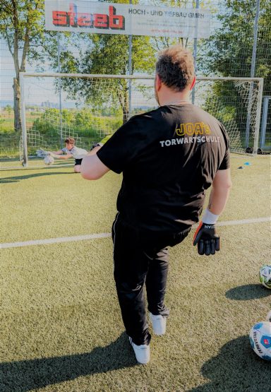 Ein Torwart steht auf dem Fußballfeld und bereitet sich auf einen Schuss vor.